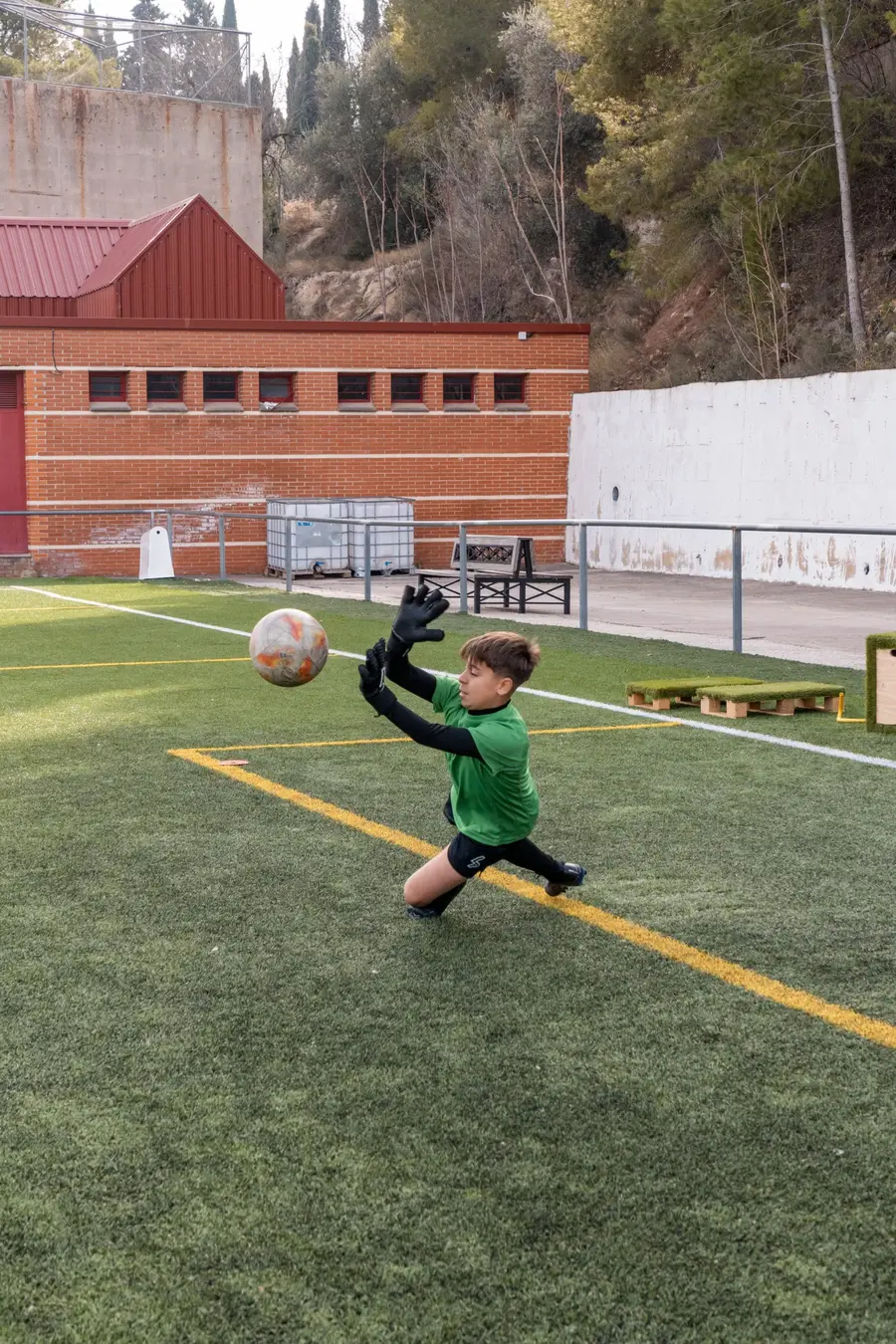 Portera con equipación verde atrapando un balón alto en plena estirada