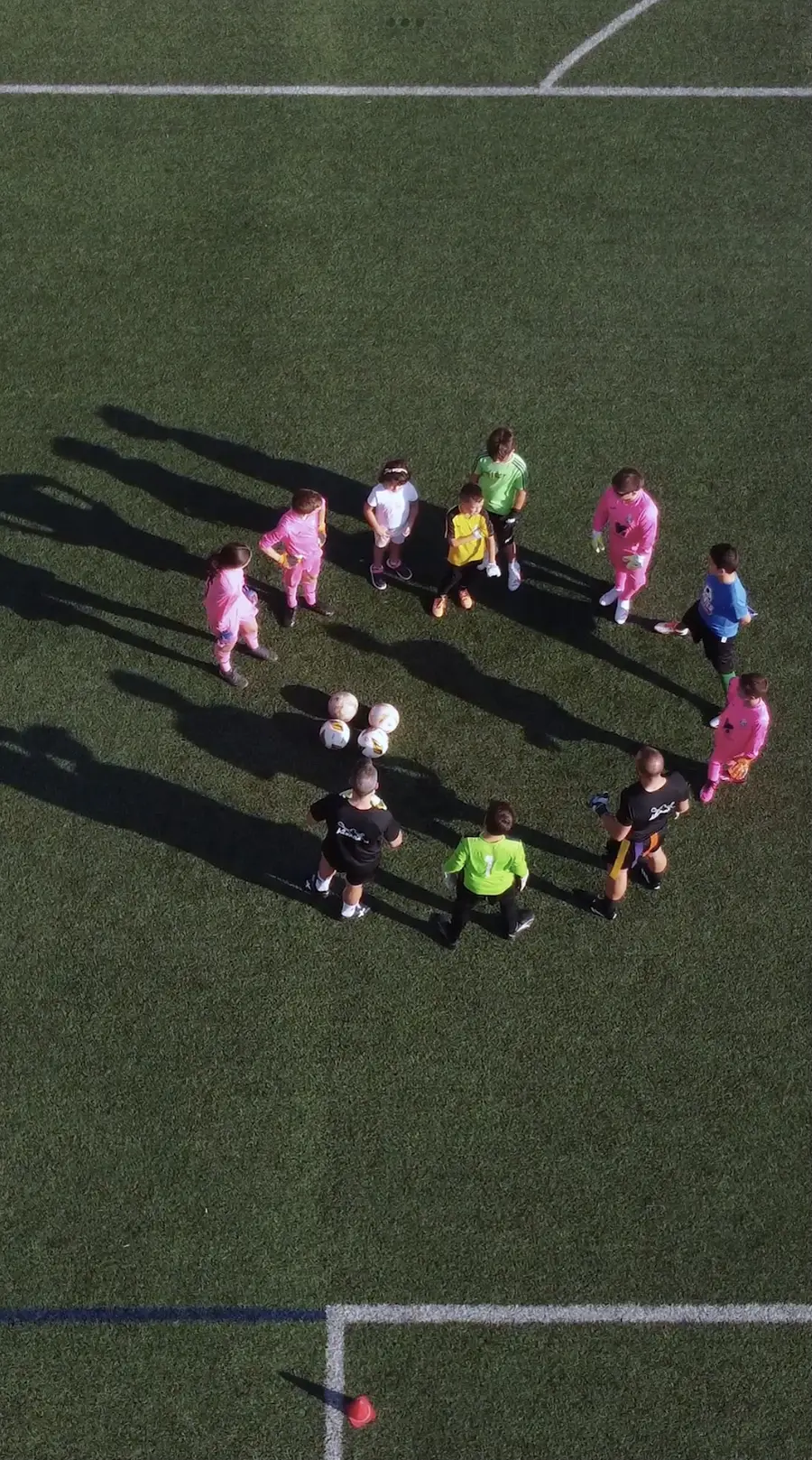 Vista aérea de un grupo de alumnos en círculo durante una charla de entrenamiento